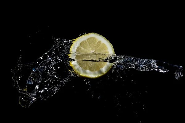 Zitronenscheiben mit Wasserspritzer auf schwarzem Hintergrund lizenzfreie Stockbilder