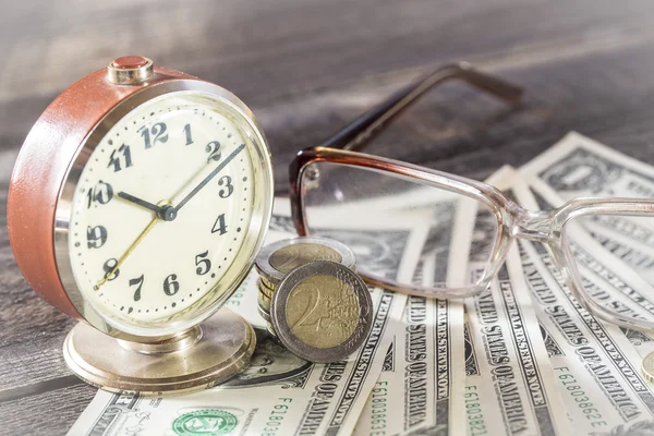 El tiempo es el concepto de finanzas monetarias con viejos relojes vintage, billetes de dólar, gafas y monedas de euro —  Fotos de Stock