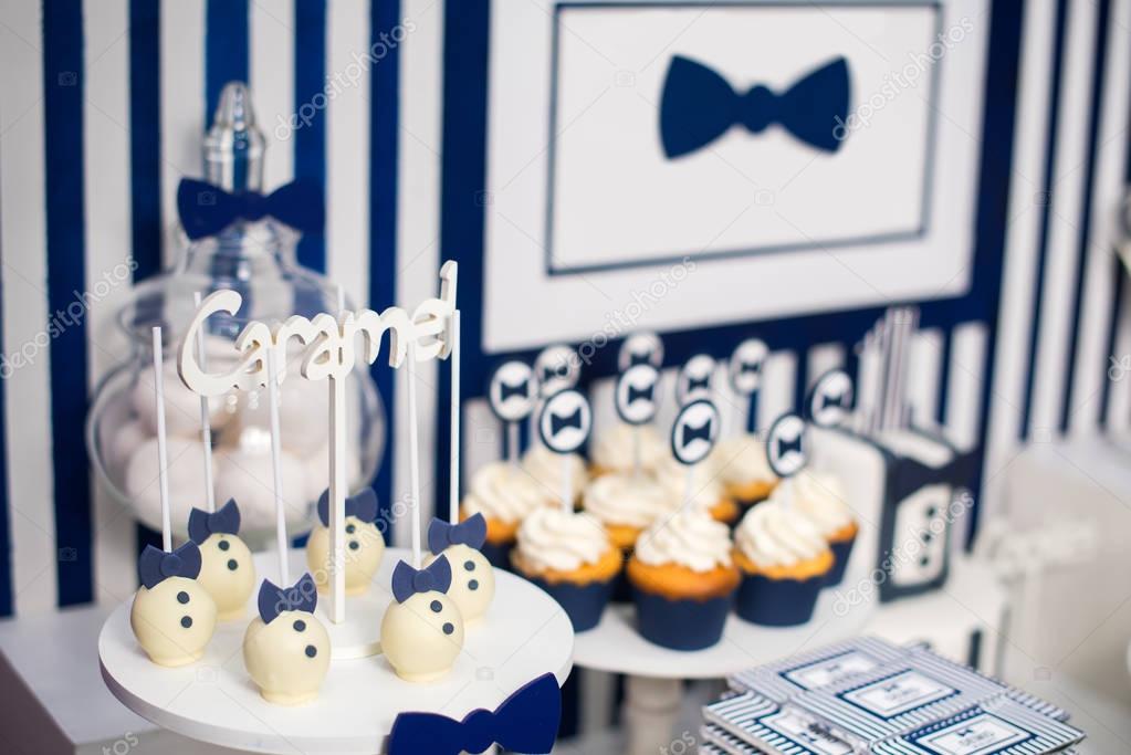 Cake, candies, marshmallows, cakepops, chocolate and other sweets on dessert table at kids birthday party. Birthday Dessert celebration candy bar in white and blue colors.