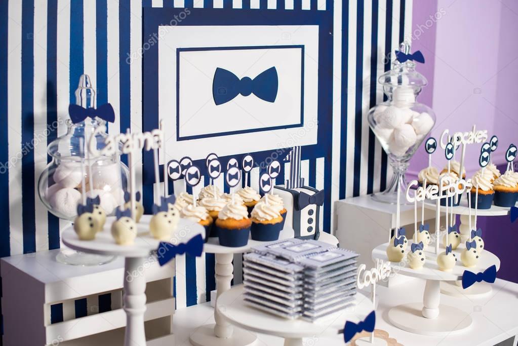 Cake, candies, marshmallows, cakepops, chocolate and other sweets on dessert table at kids birthday party. Birthday Dessert celebration candy bar in white and blue colors.