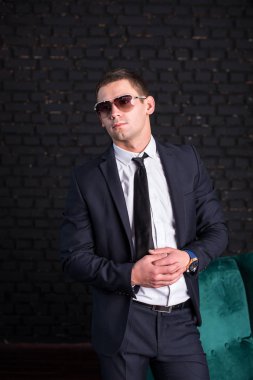 Bir siyah tuğla duvara iş elbiseli yakışıklı adam fotoğraf modeli. Başarılı moda adam