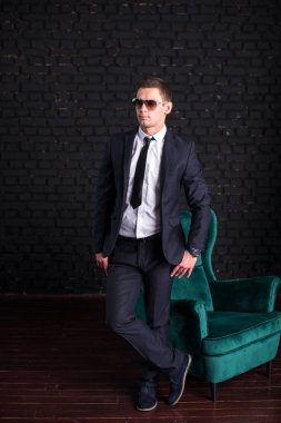 Bir siyah tuğla duvara iş elbiseli yakışıklı adam fotoğraf modeli. Başarılı moda adam