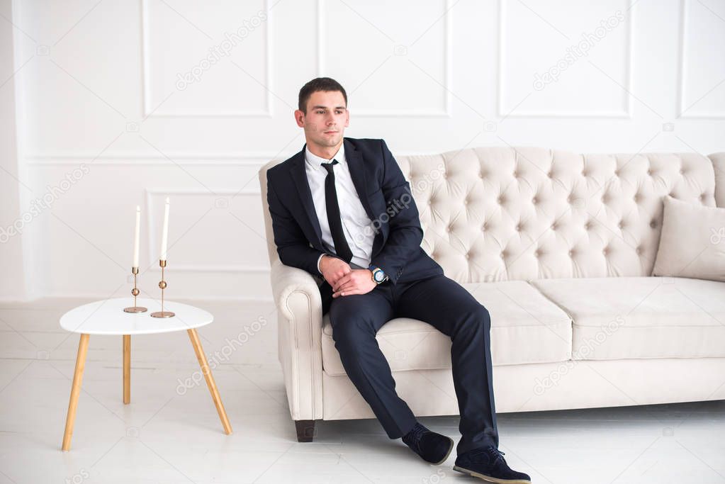Young serious and confident man in a business suit sitting on the couch
