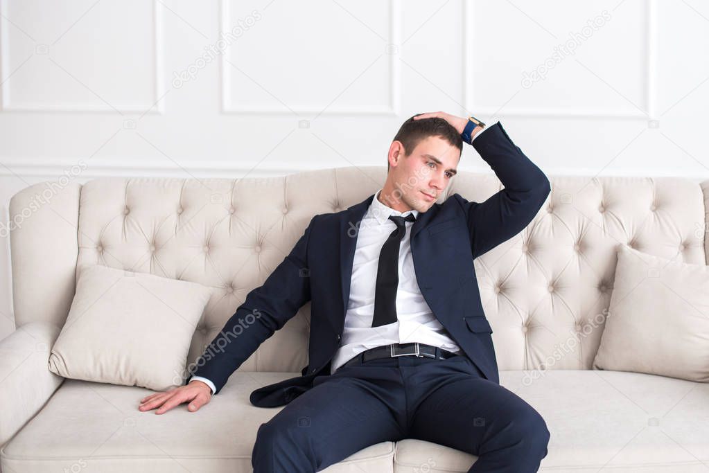Young serious and confident man in a business suit sitting on the couch