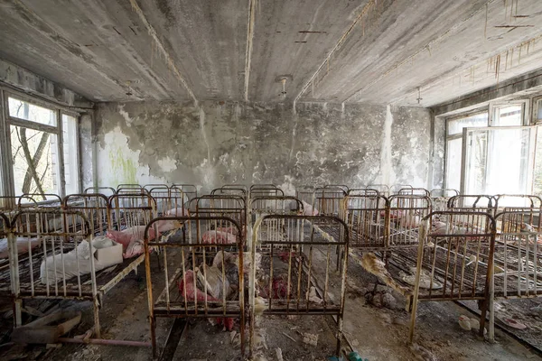 Abandoned kindergarten in Chernobyl Exclusion Zone. Lost toys, A broken doll. Atmosphere of fear and loneliness. Ukraine, ghost town Pripyat. — Stock Photo, Image