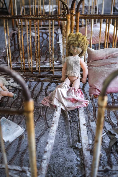 Abandoned kindergarten in Chernobyl Exclusion Zone. Lost toys, A broken doll. Atmosphere of fear and loneliness. Ukraine, ghost town Pripyat. — Stock Photo, Image