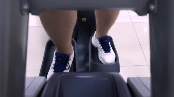 Sport, fitness, stile di vita, tecnologia e concetto di persone - primo piano delle gambe degli uomini che camminano sui tapis roulant in palestra — Video Stock