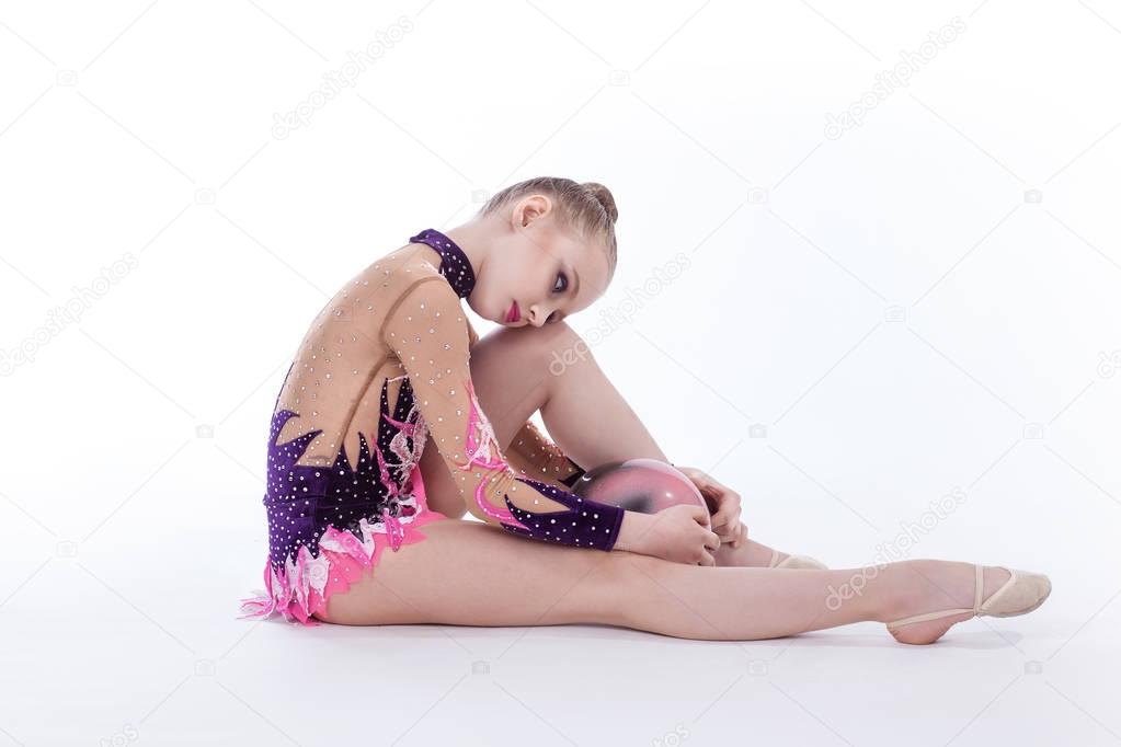 The gymnast sits on the floor