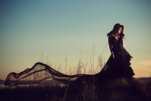 Gün batımı arka plan üzerinde uzun elbiseli kız — Stok fotoğraf