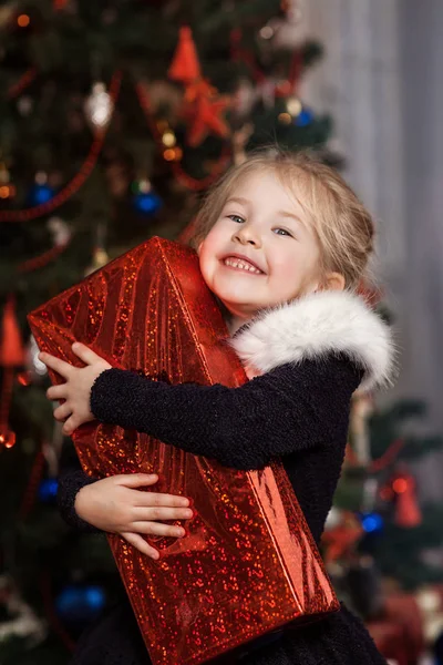 Joyeux enfant avec un cadeau près du sapin de Noël — Photo