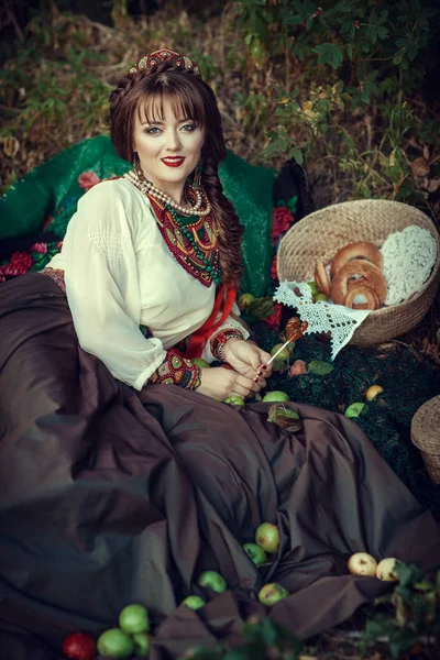 Славянская девушка на траве с яблоками — стоковое фото