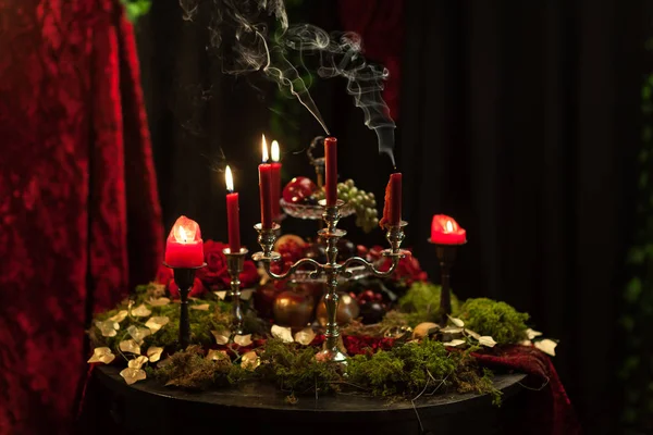 Naturaleza muerta oscura en tonos rojos con velas, musgo y rosas —  Fotos de Stock