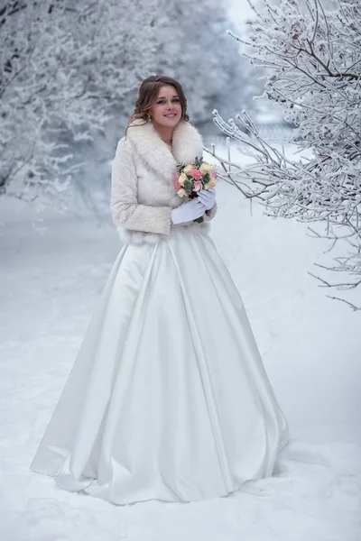 Mariée en manteau de fourrure blanche dans une rue enneigée — Photo