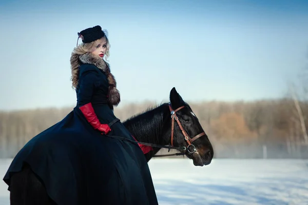 A girl in a long black dress with a dark horse — Stock Photo, Image