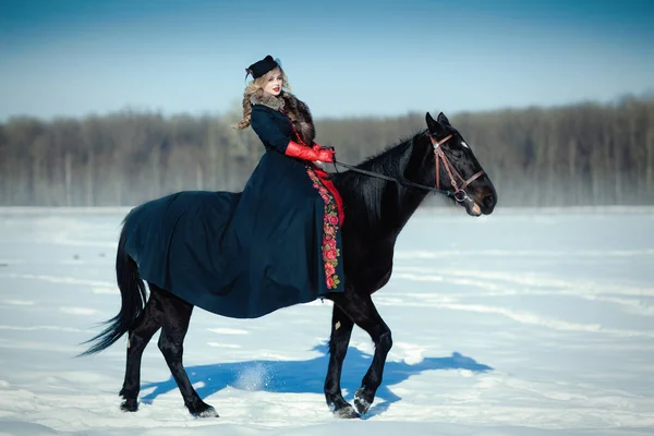 Une fille dans une longue robe noire avec un cheval sombre — Photo