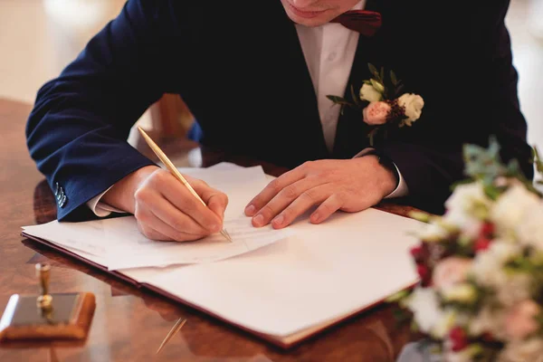 The bridegroom puts the signature on the wedding ceremony