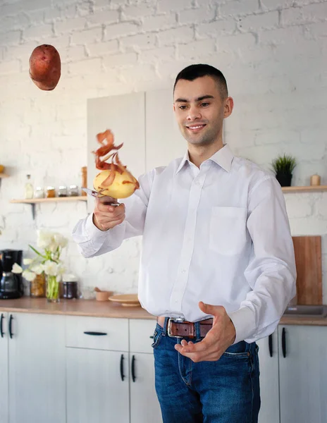 A man is peeling potatoes. Potato flies in the air