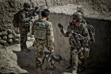 Kabul, Afghanistan - circa, 2011. Legionnaires study the terrain for further action during a combat mission. clipart