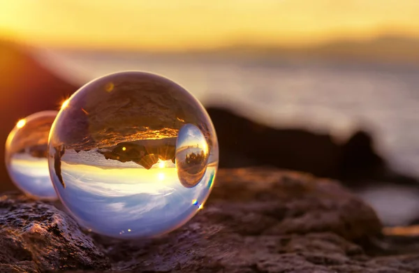 Crystal Ball Reflexión en la orilla del mar a la luz del amanecer. Reflejos de espejo en dos bolas de cristal — Foto de Stock