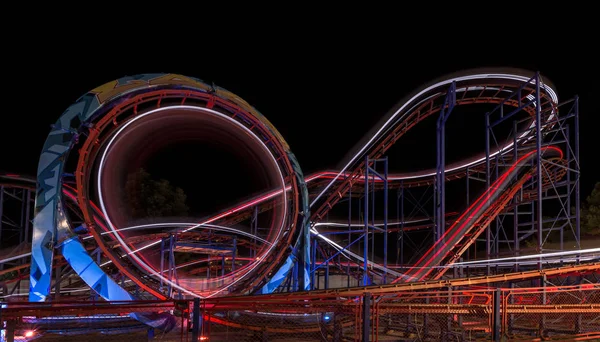 Attraction dans le parc. Roller coaster en mouvement la nuit. Une longue photo d'exposition — Photo
