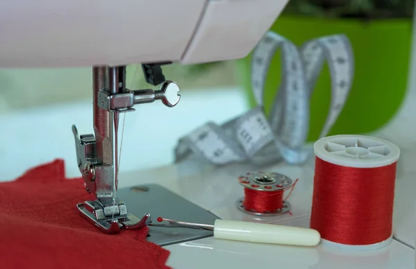 O pé da máquina de costura com uma agulha cose o tecido a cores vermelho. Detalhes da máquina de costura — Fotografia de Stock