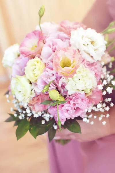 Lovely bridal bouquet of light pink ranunculus, pink and white wedding flowers and lots of green leaves fine toned in a gentle color