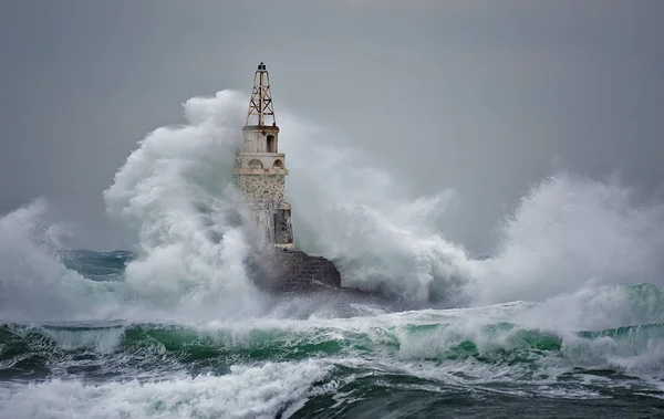 Mercusuar di Stormy Landscape. Gelombang badai melintas mercusuar Ahtopol, Laut Hitam, Bulgaria. Stok Foto