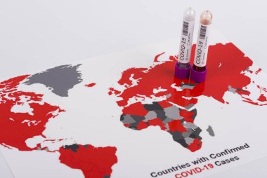 Coronavirus ve seyahat konsepti. Coronavirüs salgını, Wuhan, Çin 'de salgın. Seyahat kısıtlamaları ve karantina. COVID-19 vakası olan ülkeleri gösteren bir dünya haritasındaki bir tüpteki kan örneği