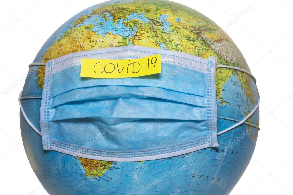 Protective surgical face mask on a terrestrial globe model. Coronavirus Concept. Surgical mask with rubber ear straps. Corona virus, nCoV, covid 19. Coronavirus outbreak.
