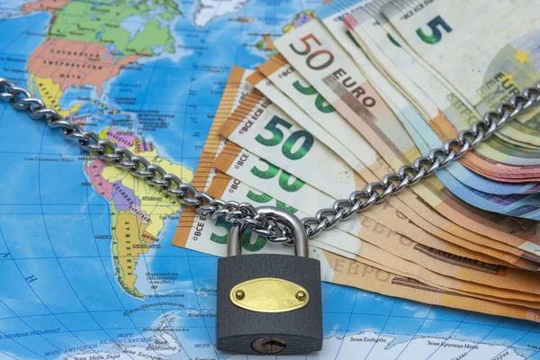 Chain , Padlock and money On A Blurred World Map .Coronavirus ,covid-19 - global security concept.