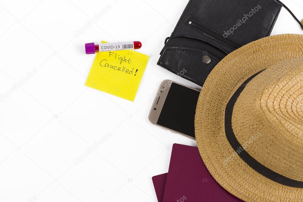 Top view of travel accessory (passport,phone, hat and wallet), note flight canceled and positive coronavirus blood test, isolated on a white background. Flight restricted and Covid-19 spread concept.