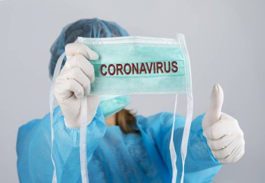 Koruyucu yüz maskesi ve dur işareti gösteren eldivenli genç bir doktor Coronavirus 'u durdur, Cvid-19. Tıbbi enfeksiyonlar konsepti durduruyor. COVID 19 kavramını durdur..