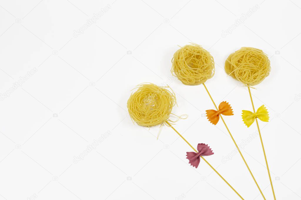 Top view flowers and butterflies made out of various pasta on white background.Copy space, place for text.