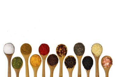 Beyaz arka planda ahşap kaşıklarda farklı aromatik baharatlar içeren kompozisyon