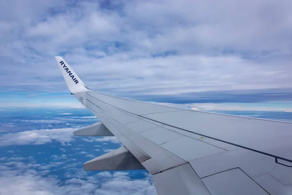 BARCELONA, SPAIN - 27.02.2020: Low-cost airline Ryanair logo on airplane\'s wing and turbine, blue sea and Athens coastline