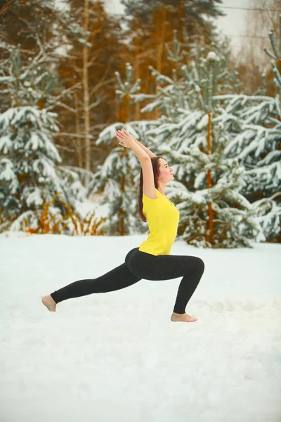 beautiful woman doing yoga outdoors in the snow