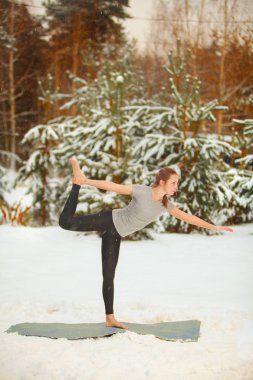 güzel kadın açık havada karda yoga yaparken 