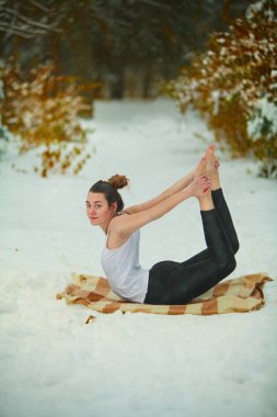 güzel kadın açık havada karda yoga yaparken 