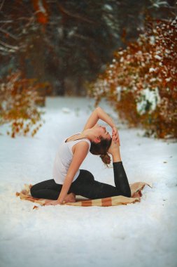güzel kadın açık havada karda yoga yaparken 