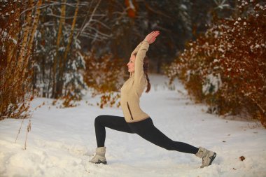 güzel kadın açık havada karda yoga yaparken 