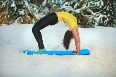 güzel kadın açık havada karda yoga yaparken 