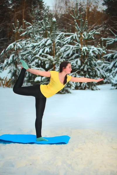 beautiful woman doing yoga outdoors in the snow