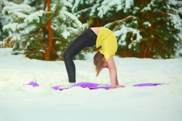 güzel kadın açık havada karda yoga yaparken 