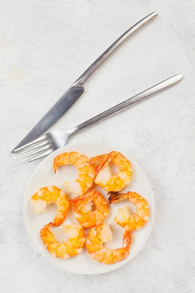 Вкусные аппетитные креветки на белой тарелке на белом — стоковое фото
