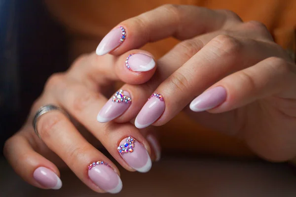 Vrouwelijke roze Franse manicure op mooie achtergrond — Stockfoto