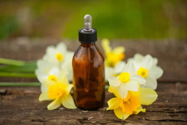 Esencia de flores en la mesa en un hermoso frasco de vidrio — Foto de Stock