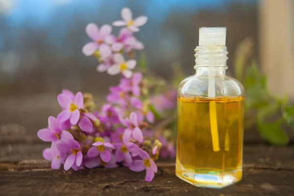 El óleo etérico de la flor arábiga sobre la mesa en la botella hermosa — Foto de Stock