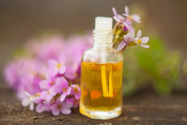 El óleo etérico de la flor arábiga sobre la mesa en la botella hermosa — Foto de Stock