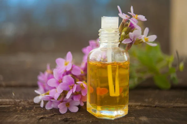 El óleo etérico de la flor arábiga sobre la mesa en la botella hermosa — Foto de Stock