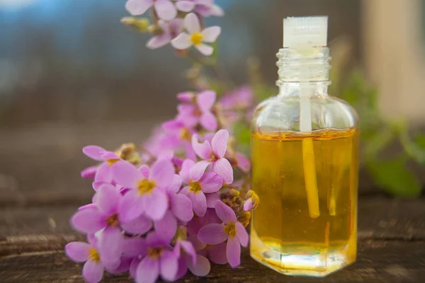 El óleo etérico de la flor arábiga sobre la mesa en la botella hermosa — Foto de Stock